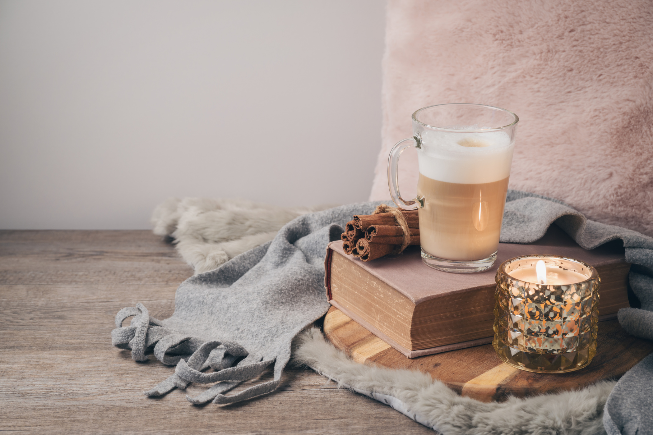 Hygge Scandinavian style concept with latte macchiato coffee cup, candles and book.